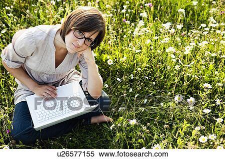 Stock Photography - Woman with laptop in wild meadow. Fotosearch