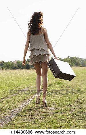 Stock Photograph - Woman with suitcase walking away. Fotosearch
