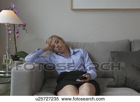 Woman with TV remote relaxing on sofa View Large Photo Image Stock Photography - Woman with TV remote relaxing on sofa. Fotosearch