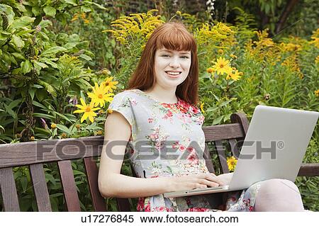 Woman working on laptop on parkbench View Large Photo Image Stock Photography - Woman working on laptop on parkbench. Fotosearch