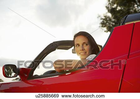 Stock Photo - Women sitting in her electric sports car. Fotosearch