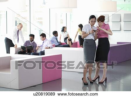 Stock Photo - Work colleagues in busy workplace. Fotosearch