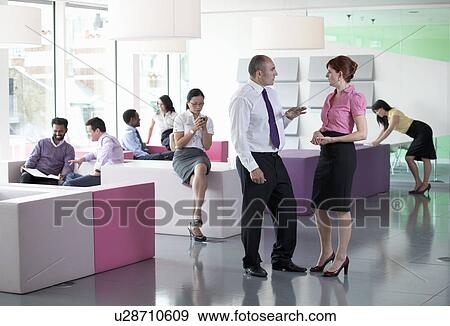 Stock Photo - Work colleagues in busy workplace. Fotosearch