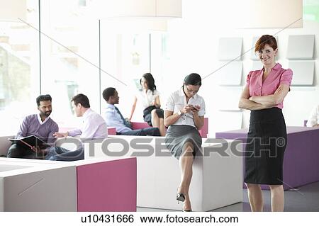 Stock Photograph - Work colleagues in busy workplace. Fotosearch