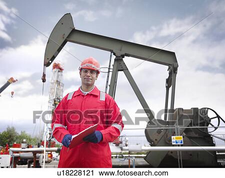Worker in front of oil well pump View Large Photo Image Stock Image - Worker in front of oil well pump. Fotosearch