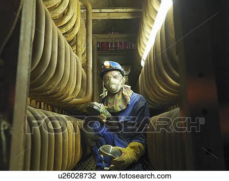 Stock Image - Worker repairing a furnace. Fotosearch