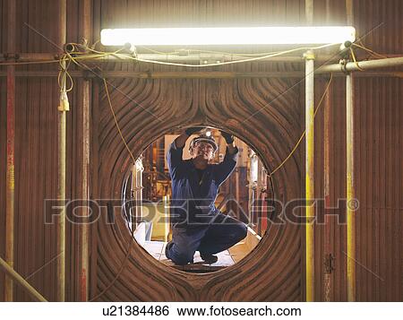 Stock Photograph - Worker repairing a furnace. Fotosearch