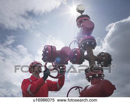 Stock Photography - Worker turning valve on oil well. Fotosearch