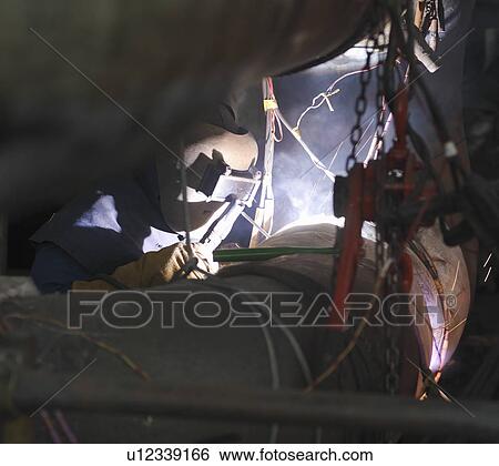Stock Photograph - Worker welding in a power station. Fotosearch