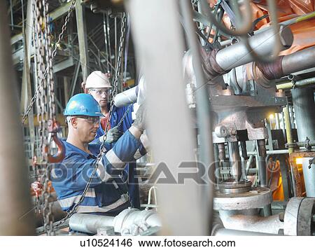 Stock Photograph - Workers fit a valve in a power station. Fotosearch