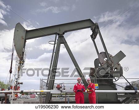 Workers in front of oil well pump View Large Photo Image Stock Image - Workers in front of oil well pump. Fotosearch