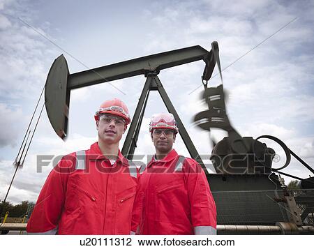 Workers in front of oil well pump View Large Photo Image Stock Image - Workers in front of oil well pump. Fotosearch