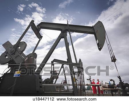 Workers next to oil well pump View Large Photo Image Stock Image - Workers next to oil well pump. Fotosearch