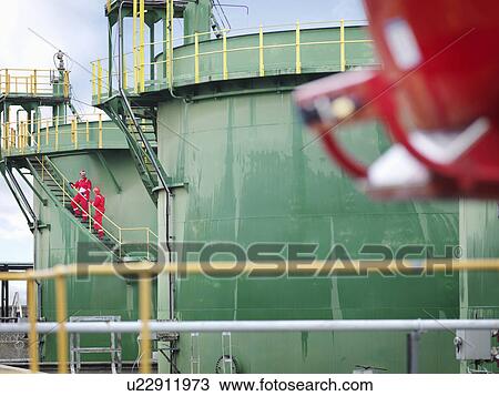 Stock Image - Workers on steps of oil tank. Fotosearch