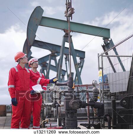 Workers taking reading at oil well View Large Photo Image Stock Photo - Workers taking reading at oil well. Fotosearch