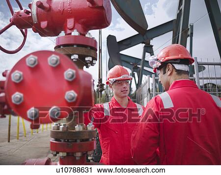 Stock Image - Workers talking by oil wells. Fotosearch