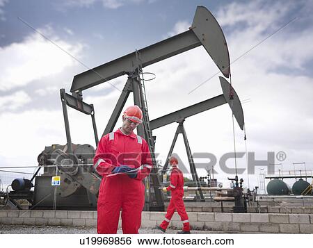 Workers with clipboard next to oil well View Large Photo Image Stock Photograph - Workers with clipboard next to oil well. Fotosearch