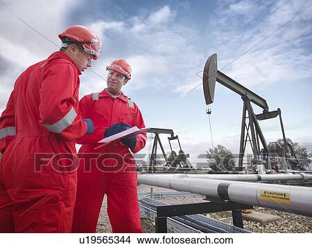 Picture - Workers with oil wells. Fotosearch