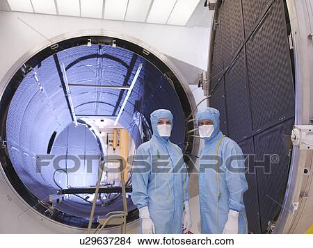 Picture - Workers with satellite testing chamber. Fotosearch