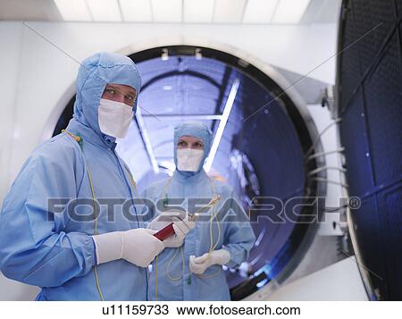 Stock Image - Workers with satellite testing chamber. Fotosearch