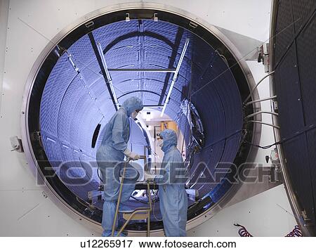 Stock Photo - Workers with satellite testing chamber. Fotosearch