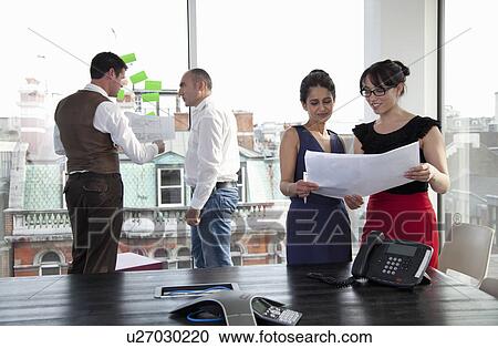 Stock Image - Workmates looking at plans. Fotosearch