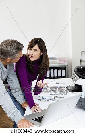 Stock Photo - Workmates talking about project. Fotosearch