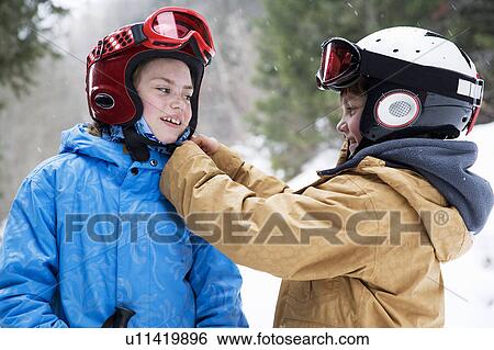 Stock Photograph - Young boy helping girl do up ski helmet. Fotosearch