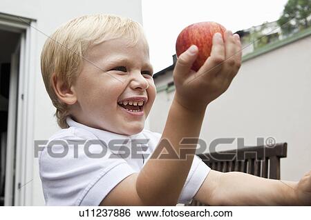 Stock Photograph - Young Boy holding apple in his hand. Fotosearch