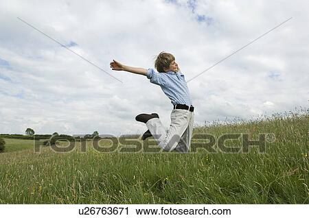 Young boy jumping in field View Large Photo Image Stock Image - Young boy jumping in field. Fotosearch