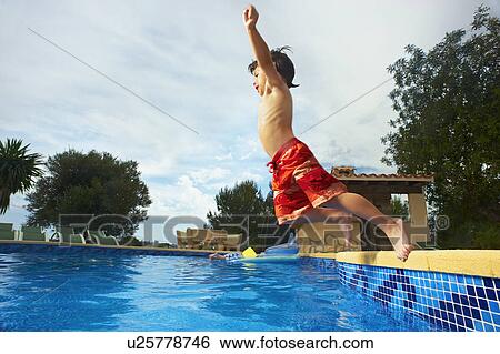 Stock Photograph - Young boy jumping into swimming pool. Fotosearch