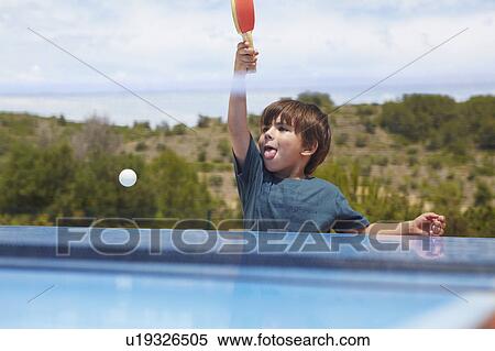 Stock Photography - Young boy playing table tennis outdoors. Fotosearch