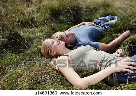 Stock Image - Young couple laying in grass. Fotosearch