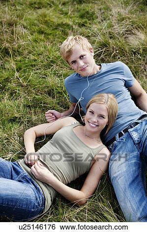 Young couple laying in grass View Large Photo Image Stock Photograph - Young couple laying in grass. Fotosearch