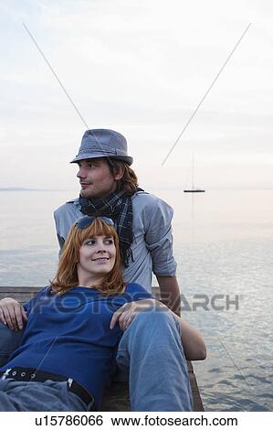 Young couple relaxing on jetty View Large Photo Image Stock Photograph - Young couple relaxing on jetty. Fotosearch