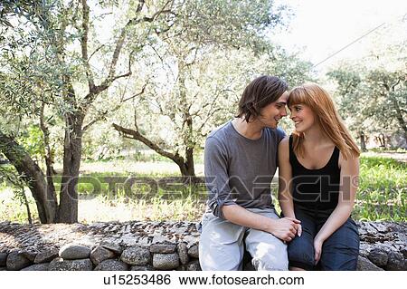 Stock Photograph - Young couple sitting on wall. Fotosearch