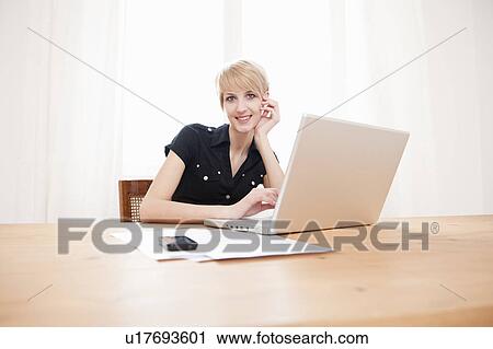 Stock Image - Young female using a laptop at home. Fotosearch