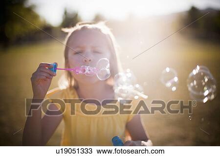 Stock Image - Young girl blowing bubbles. Fotosearch