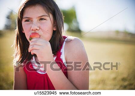 Stock Photography - Young girl eating strawberry. Fotosearch