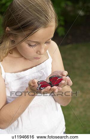 Stock Photograph - Young girl holding butterfly. Fotosearch