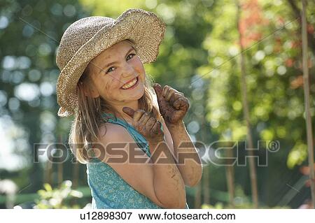Stock Photo - Young girl in garden with muddy hands. Fotosearch