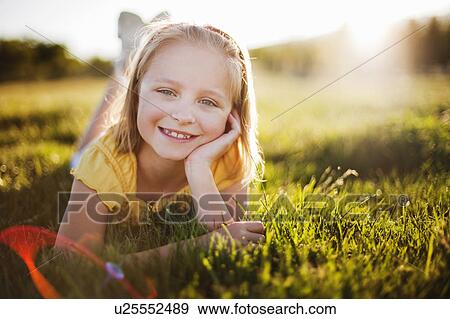 Stock Photo - Young girl in grass smiling. Fotosearch