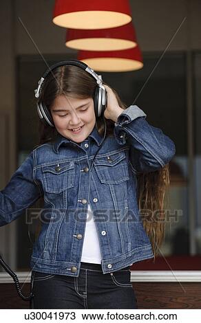 Young girl listening on headphones View Large Photo Image Stock Image - Young girl listening on headphones. Fotosearch