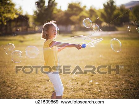 Young girl making large bubble in park View Large Photo Image Stock Photo - Young girl making large bubble in park. Fotosearch
