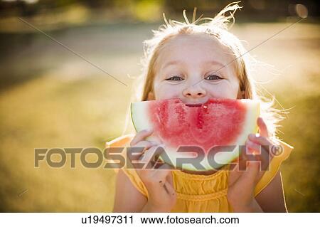 Stock Image - Young girl making smile with watermelon. Fotosearch