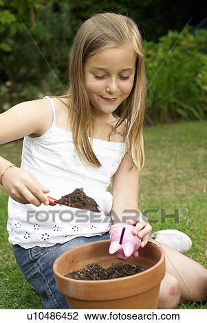 Stock Image - Young girl planting a piggy bank. Fotosearch