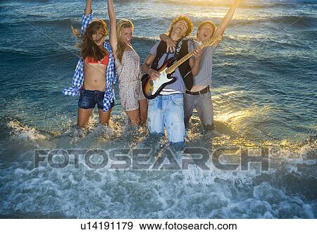 Young group sing with guitar in tide sea View Large Photo Image Stock Photo - Young group sing with guitar in tide sea. Fotosearch