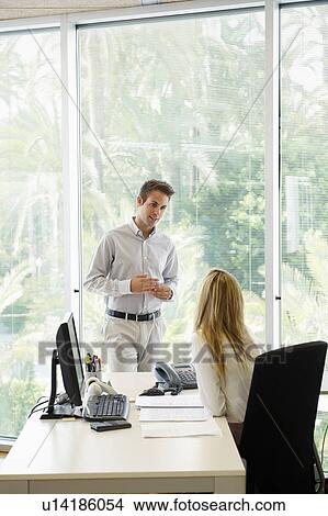 Young man chatting with woman in office View Large Photo Image Picture - Young man chatting with woman in office. Fotosearch