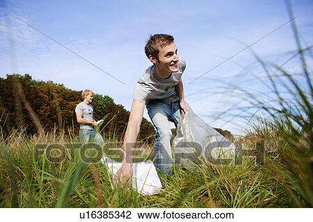 Stock Image - Young man collecting trash in nature. Fotosearch