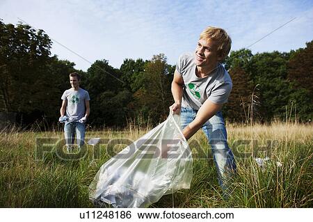 Stock Photograph - Young man collecting trash in nature. Fotosearch